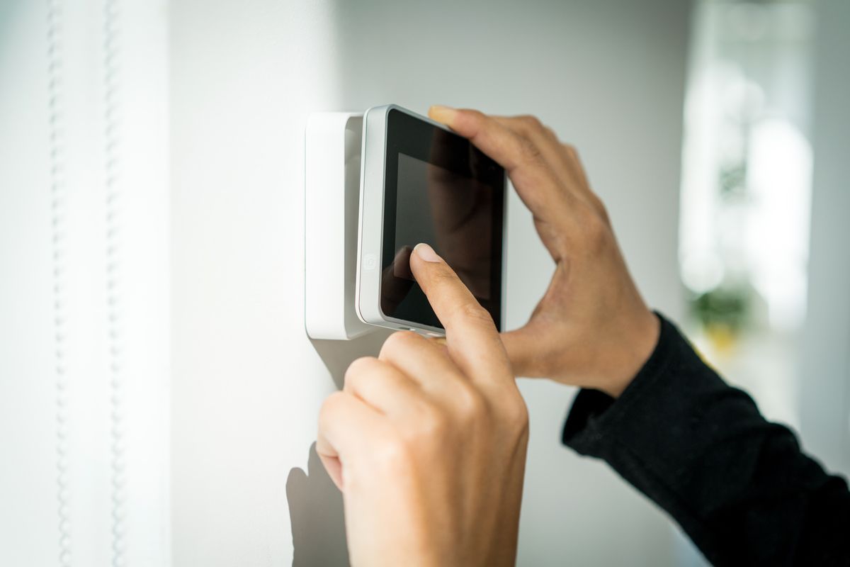 Trigger technician mounting a touchscreen security alarm panel for an Edmonton home